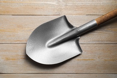 Photo of Metal shovel on light wooden table, top view