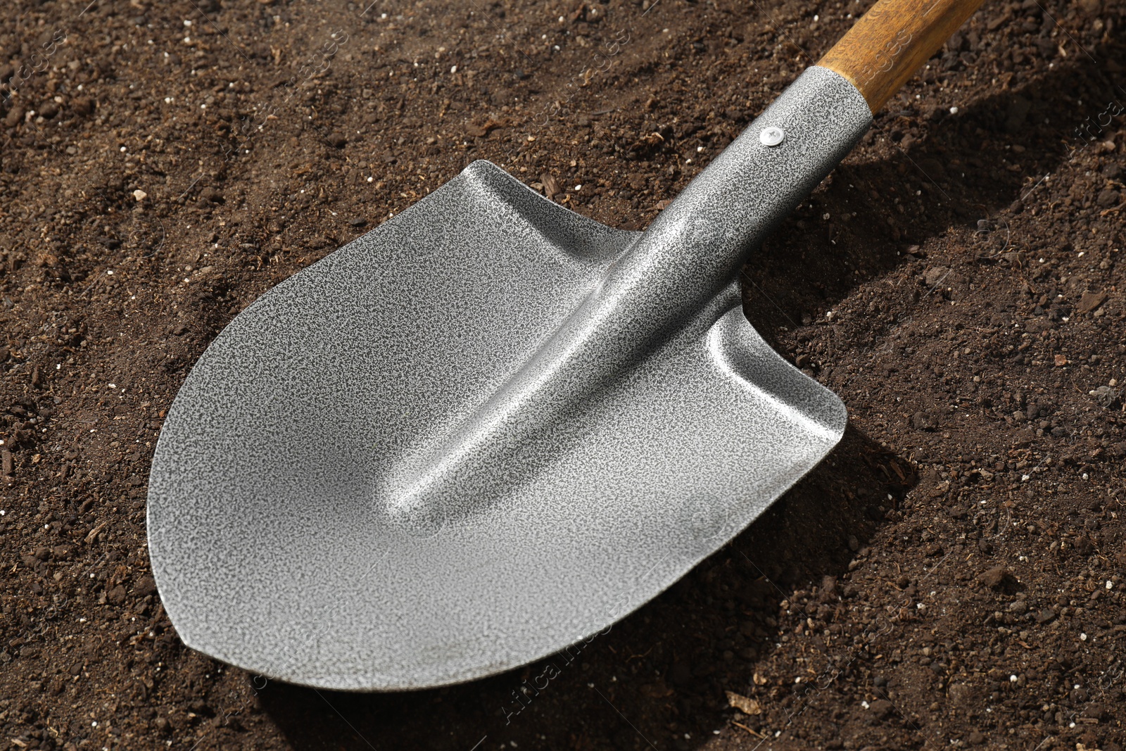 Photo of Metal shovel on pile of soil, closeup