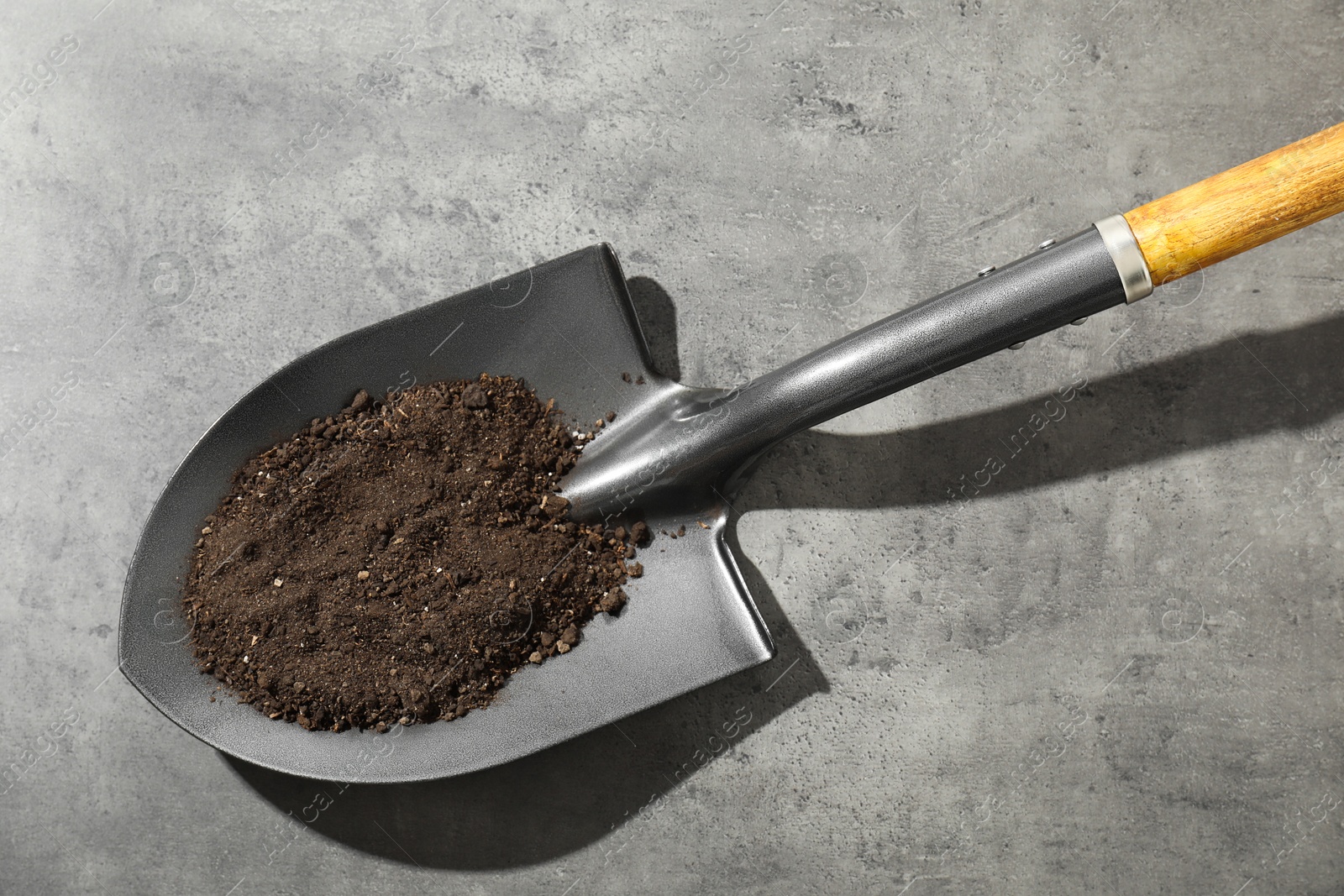 Photo of Metal shovel with soil on grey table, top view