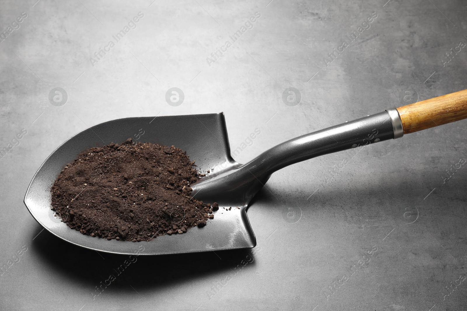 Photo of Metal shovel with soil on grey table