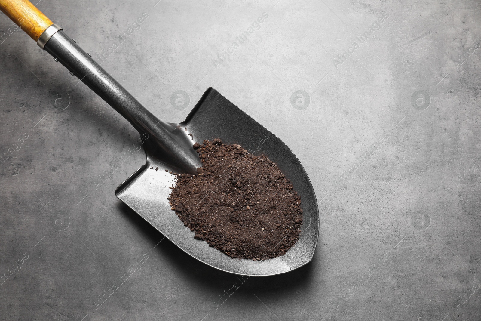 Photo of Metal shovel with soil on grey table, top view. Space for text