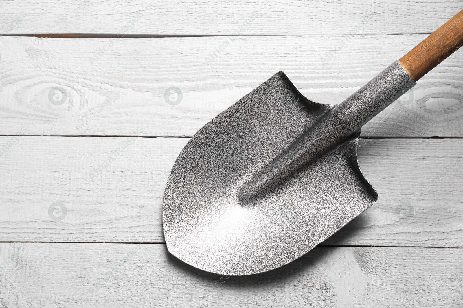 Photo of Metal shovel on light grey wooden table, top view