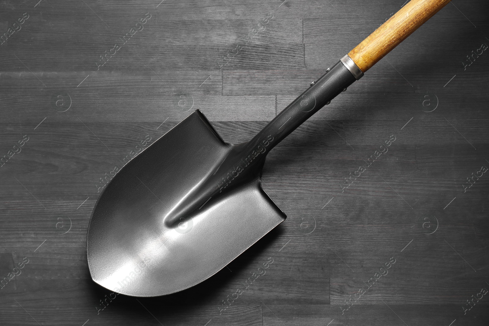 Photo of Metal shovel on black wooden table, top view