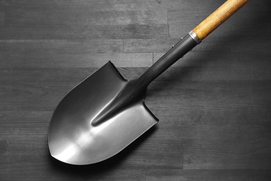 Photo of Metal shovel on black wooden table, top view