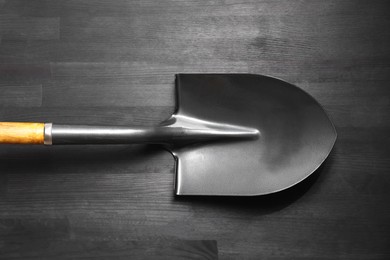 Photo of Metal shovel on black wooden table, top view