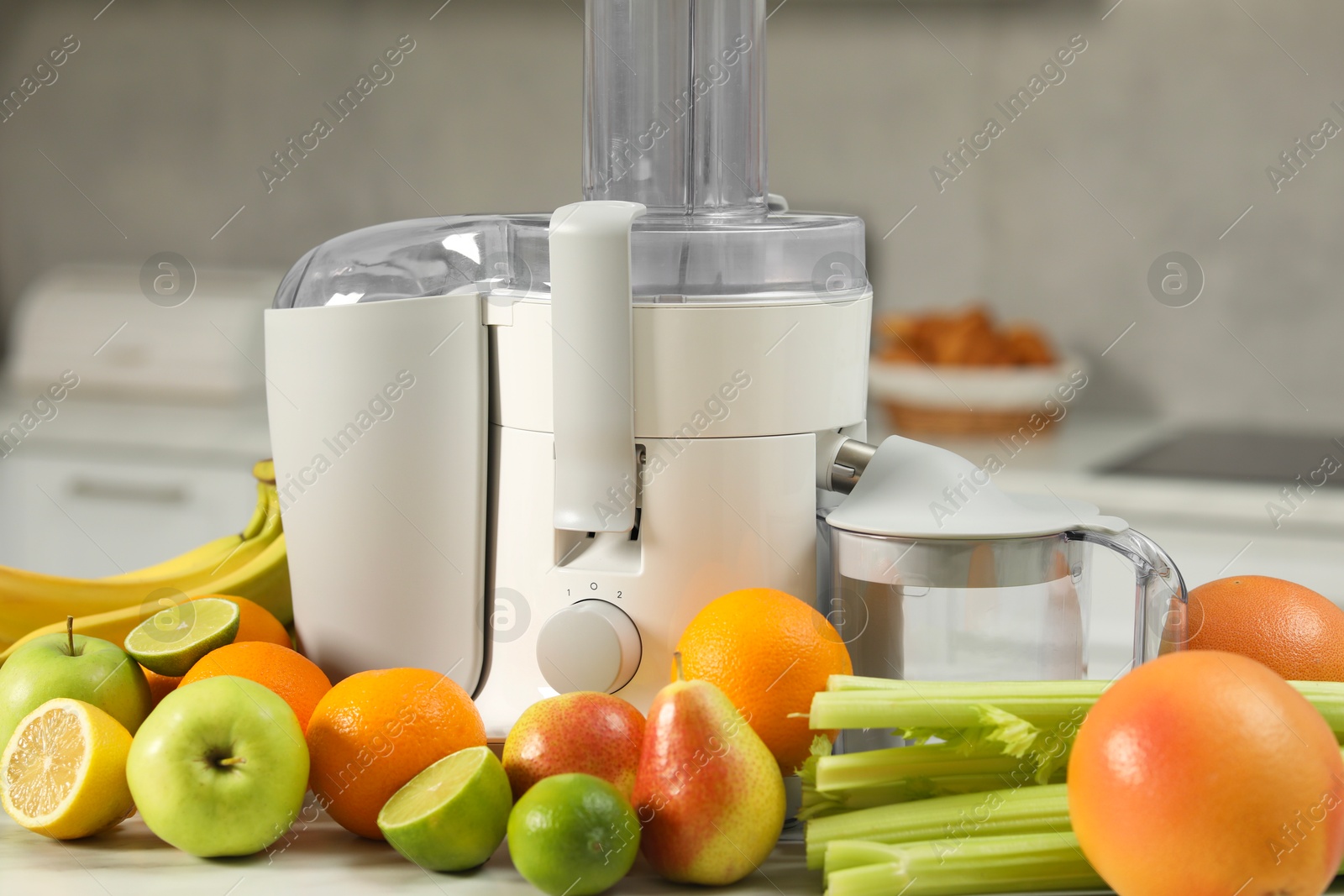 Photo of Modern juicer and fruits on white marble table in kitchen