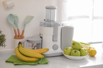 Photo of Modern juicer and fruits on white counter in kitchen