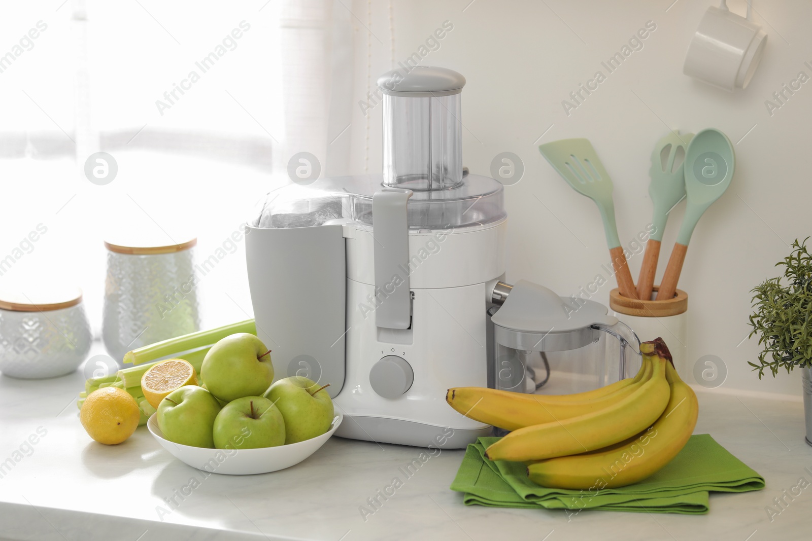 Photo of Modern juicer and fruits on white counter in kitchen