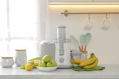 Photo of Modern juicer and fruits on white counter in kitchen