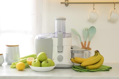 Photo of Modern juicer and fruits on white counter in kitchen