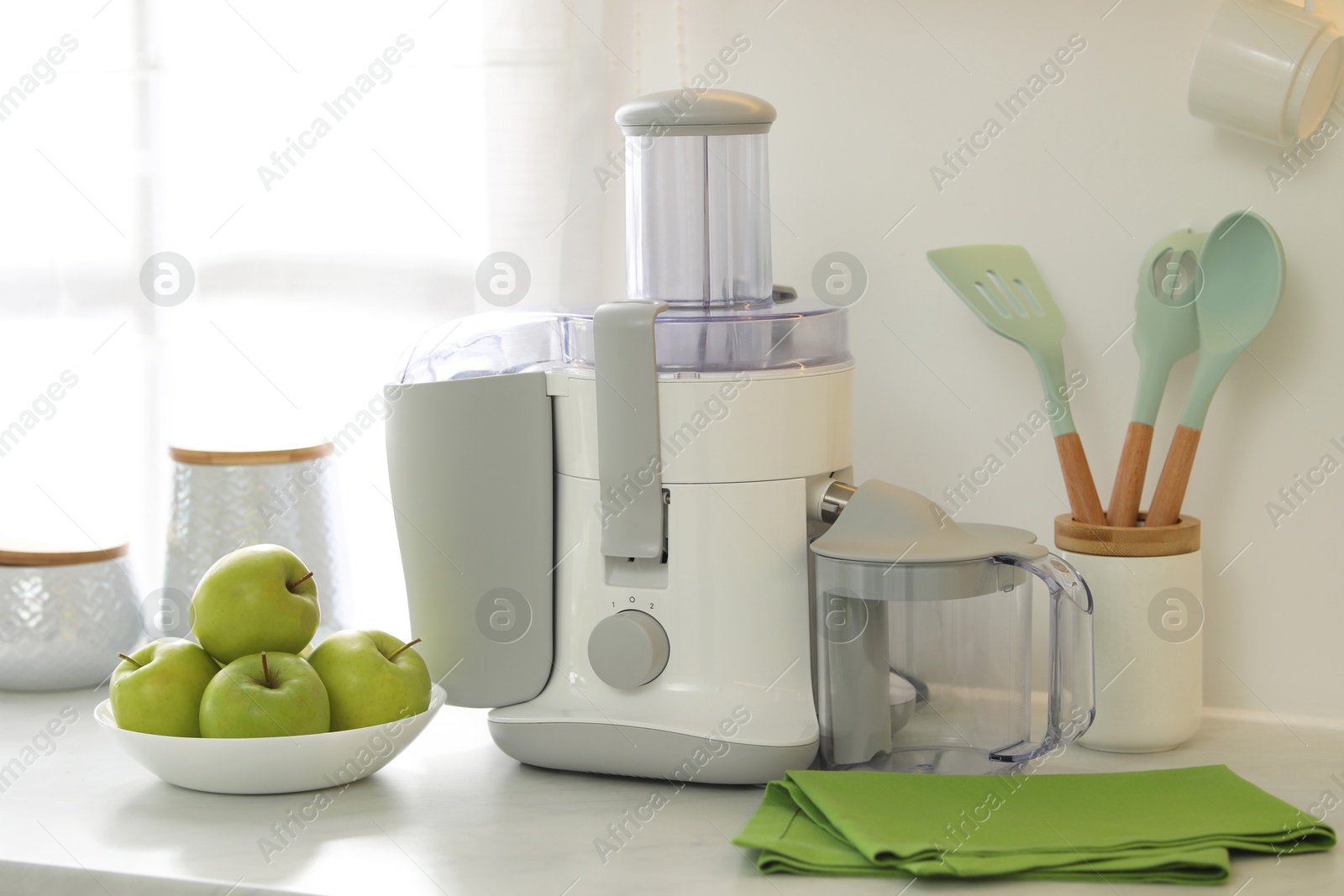 Photo of Modern juicer and apples on white counter in kitchen