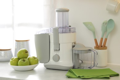 Photo of Modern juicer and apples on white counter in kitchen