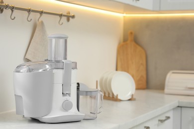 Photo of Modern juicer on white marble counter in kitchen