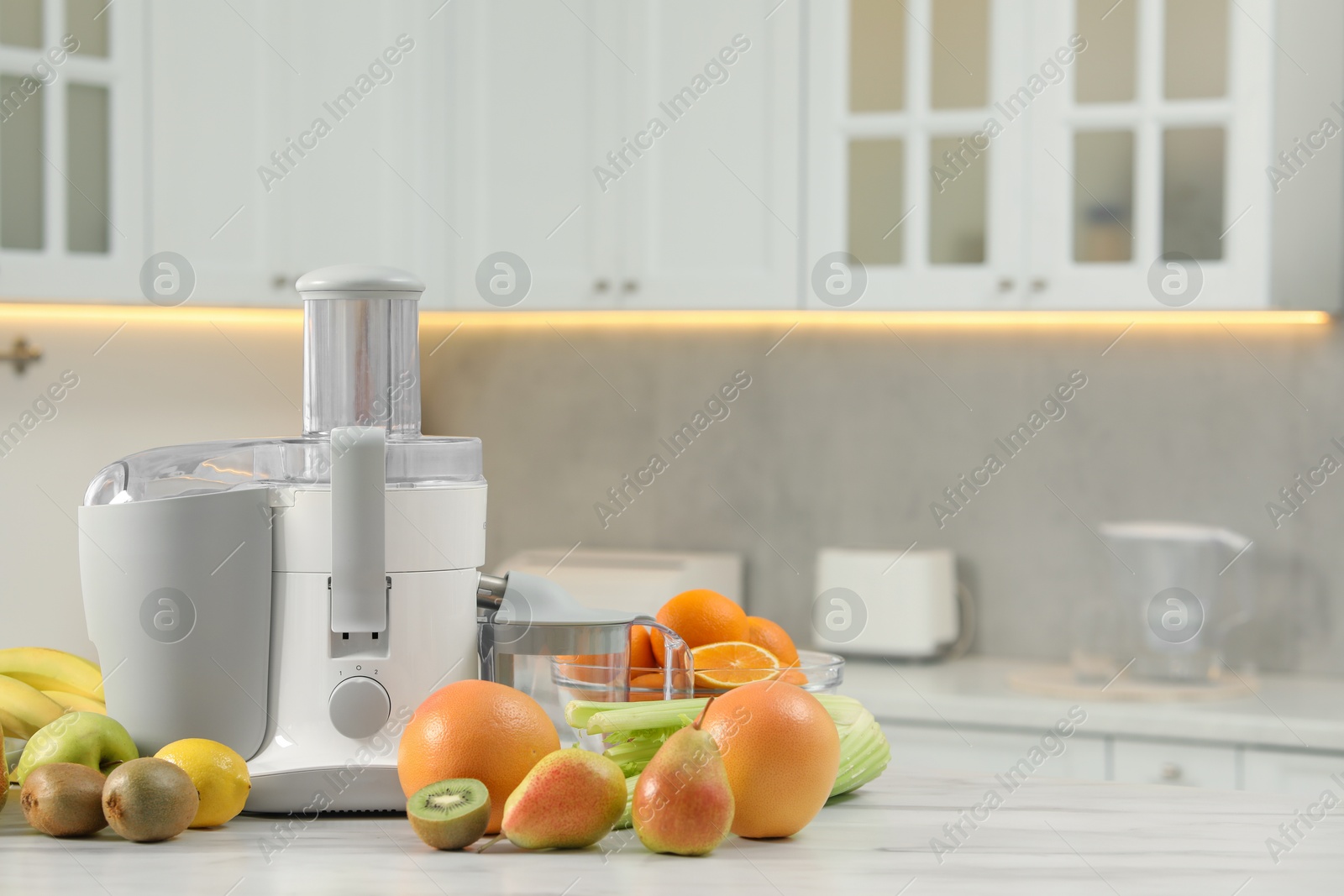 Photo of Modern juicer and fruits on white marble table in kitchen, space for text