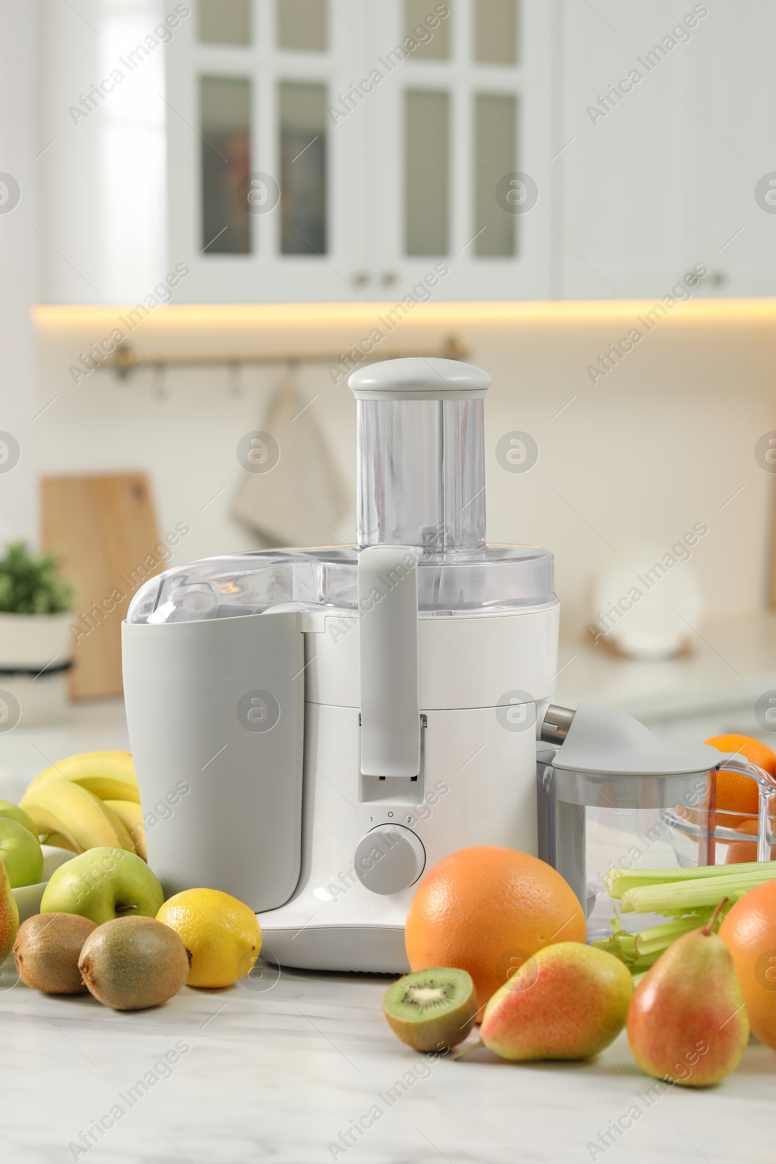 Photo of Modern juicer and fruits on white marble table in kitchen