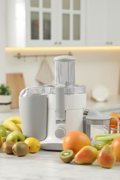 Photo of Modern juicer and fruits on white marble table in kitchen