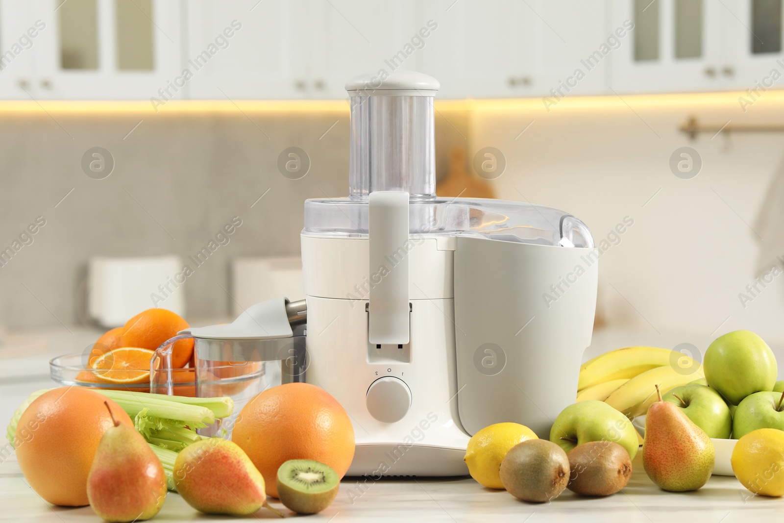 Photo of Modern juicer and fruits on white marble table in kitchen