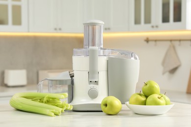 Photo of Modern juicer, celery and apples on white marble table in kitchen