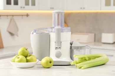 Photo of Modern juicer, celery and apples on white marble table in kitchen