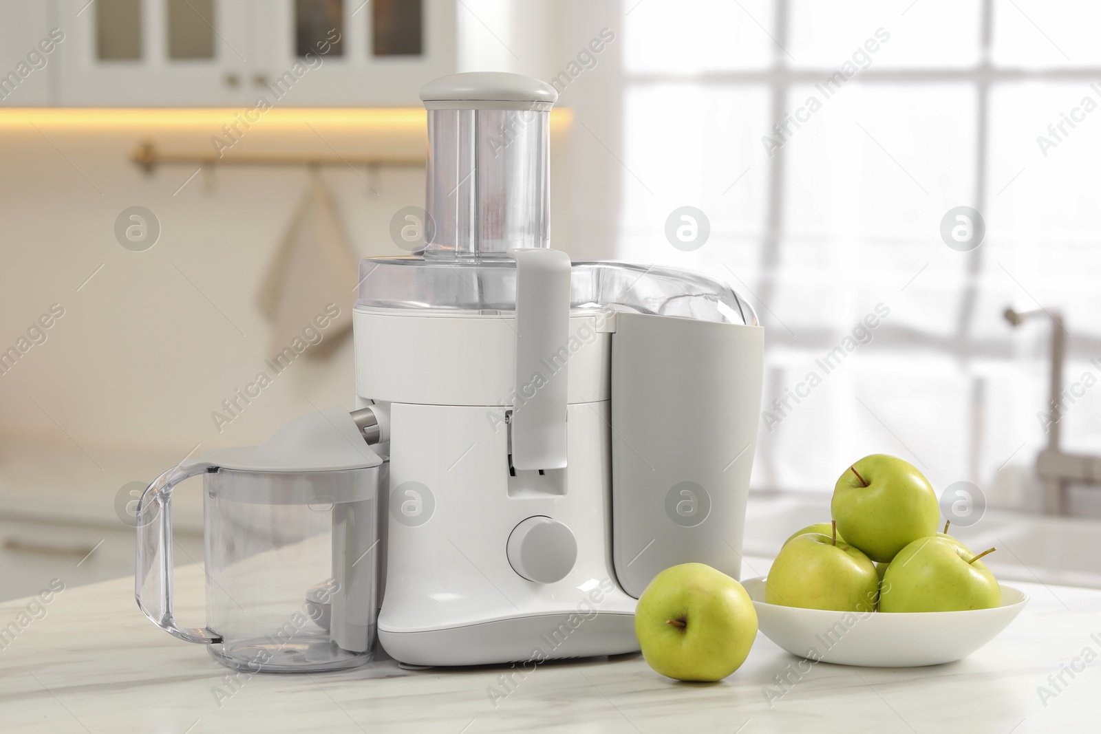 Photo of Modern juicer and apples on white marble table in kitchen