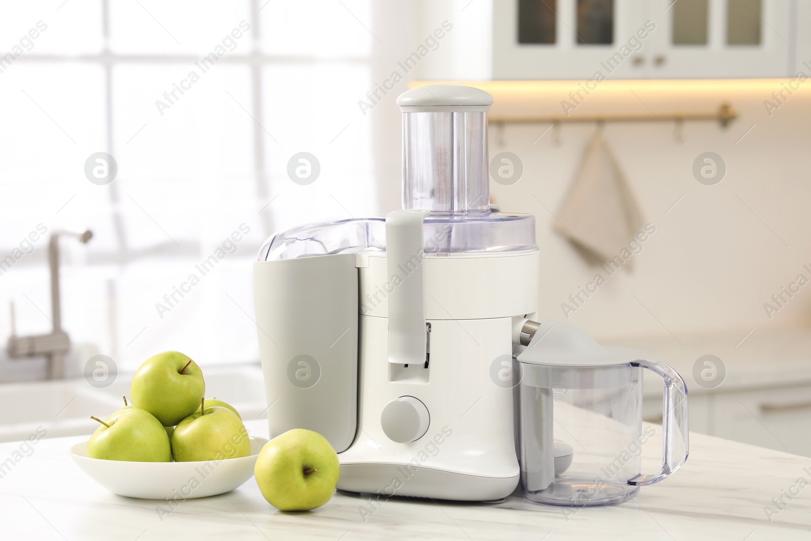 Photo of Modern juicer and apples on white marble table in kitchen