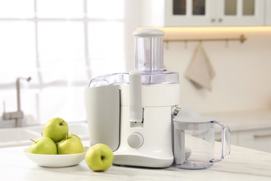 Modern juicer and apples on white marble table in kitchen