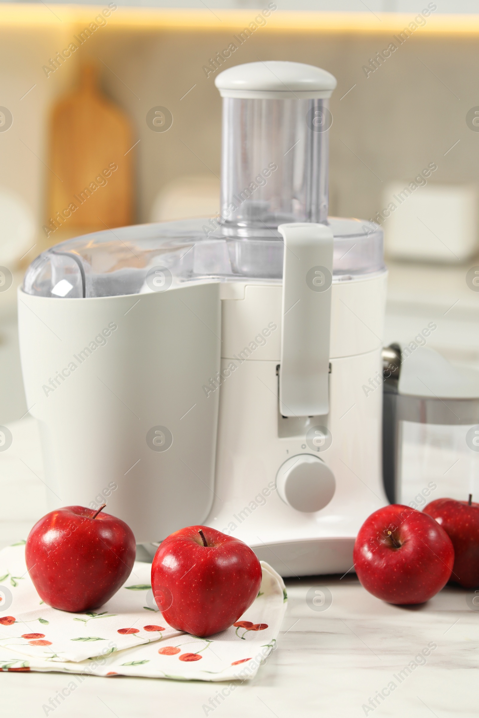 Photo of Modern juicer and apples on white marble table in kitchen