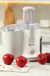 Modern juicer and apples on white marble table in kitchen