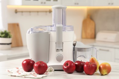 Photo of Modern juicer, pears and apples on white marble table in kitchen