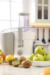 Photo of Modern juicer and fruits on white marble table in kitchen