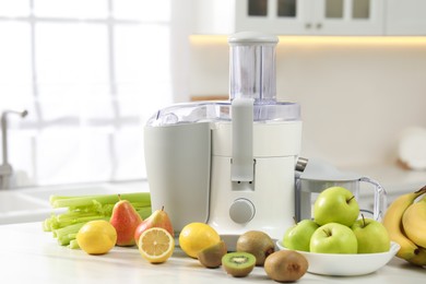 Photo of Modern juicer and fruits on white marble table in kitchen