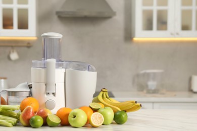 Photo of Modern juicer and fruits on white marble table, space for text