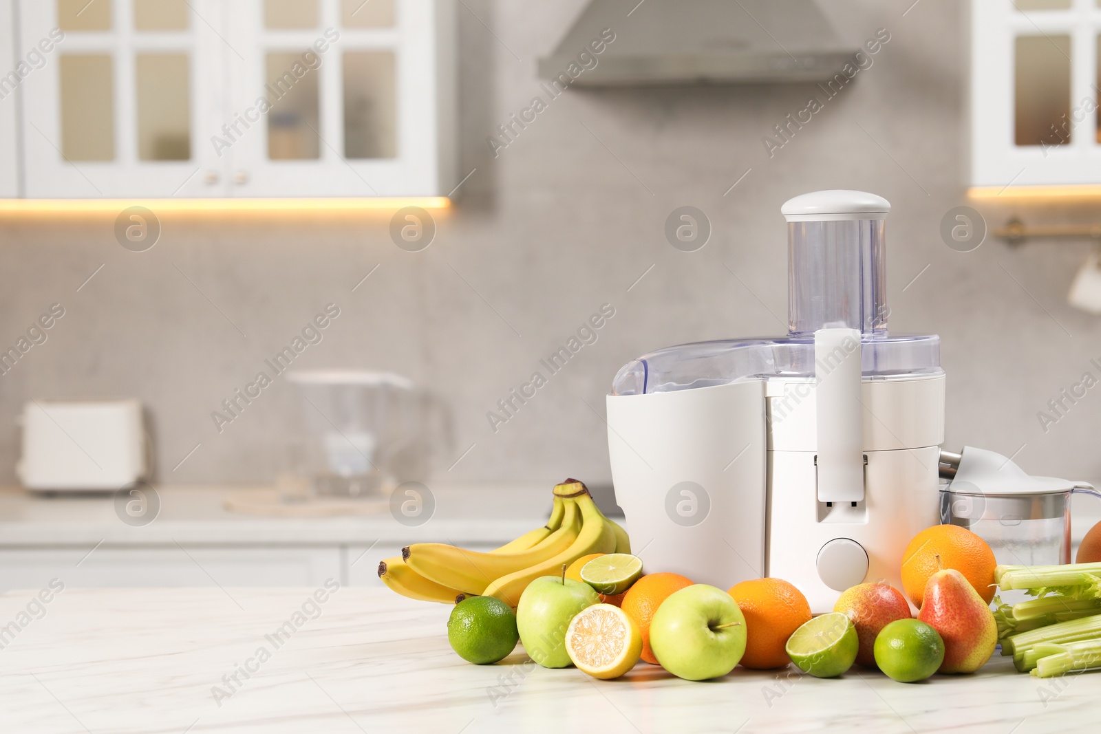 Photo of Modern juicer and fruits on white marble table, space for text