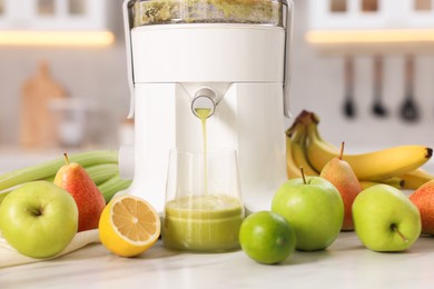 Photo of Modern juicer, fruits and glass on white marble table, closeup