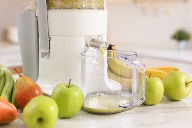 Photo of Modern juicer, fruits and mug on white marble table, closeup