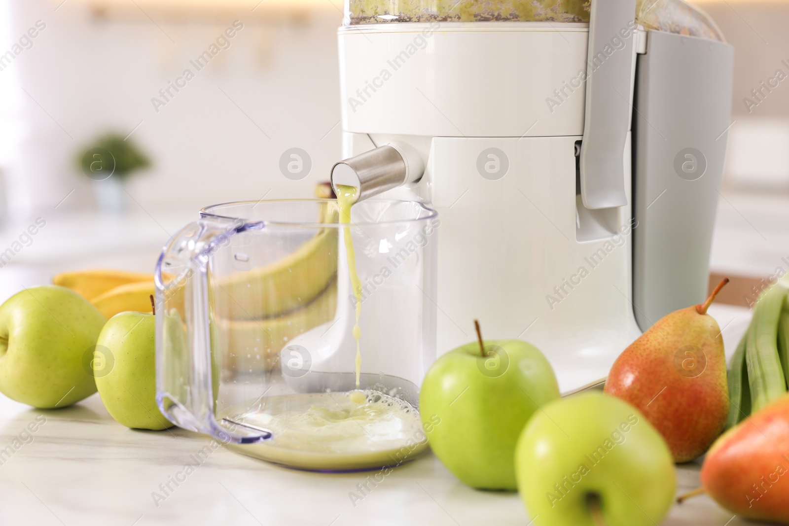 Photo of Modern juicer, fruits and mug on white marble table, closeup