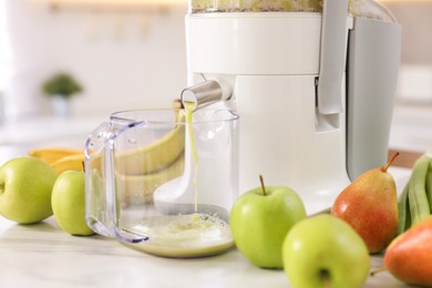 Photo of Modern juicer, fruits and mug on white marble table, closeup