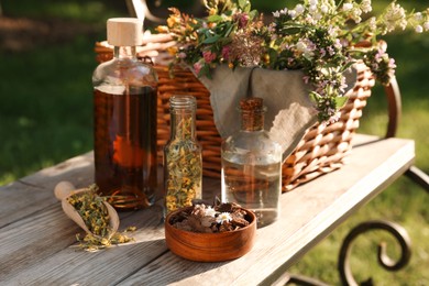 Different tinctures in bottles, bark chips and flowers on wooden bench outdoors