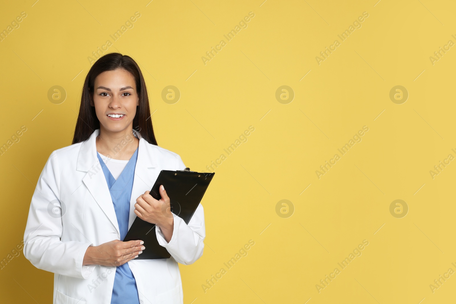 Photo of Portrait of smiling nurse with clipboard on yellow background. Space for text