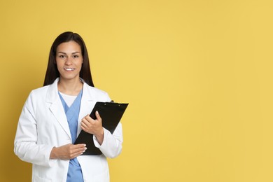 Photo of Portrait of smiling nurse with clipboard on yellow background. Space for text