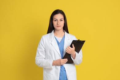 Photo of Portrait of beautiful nurse with clipboard on yellow background