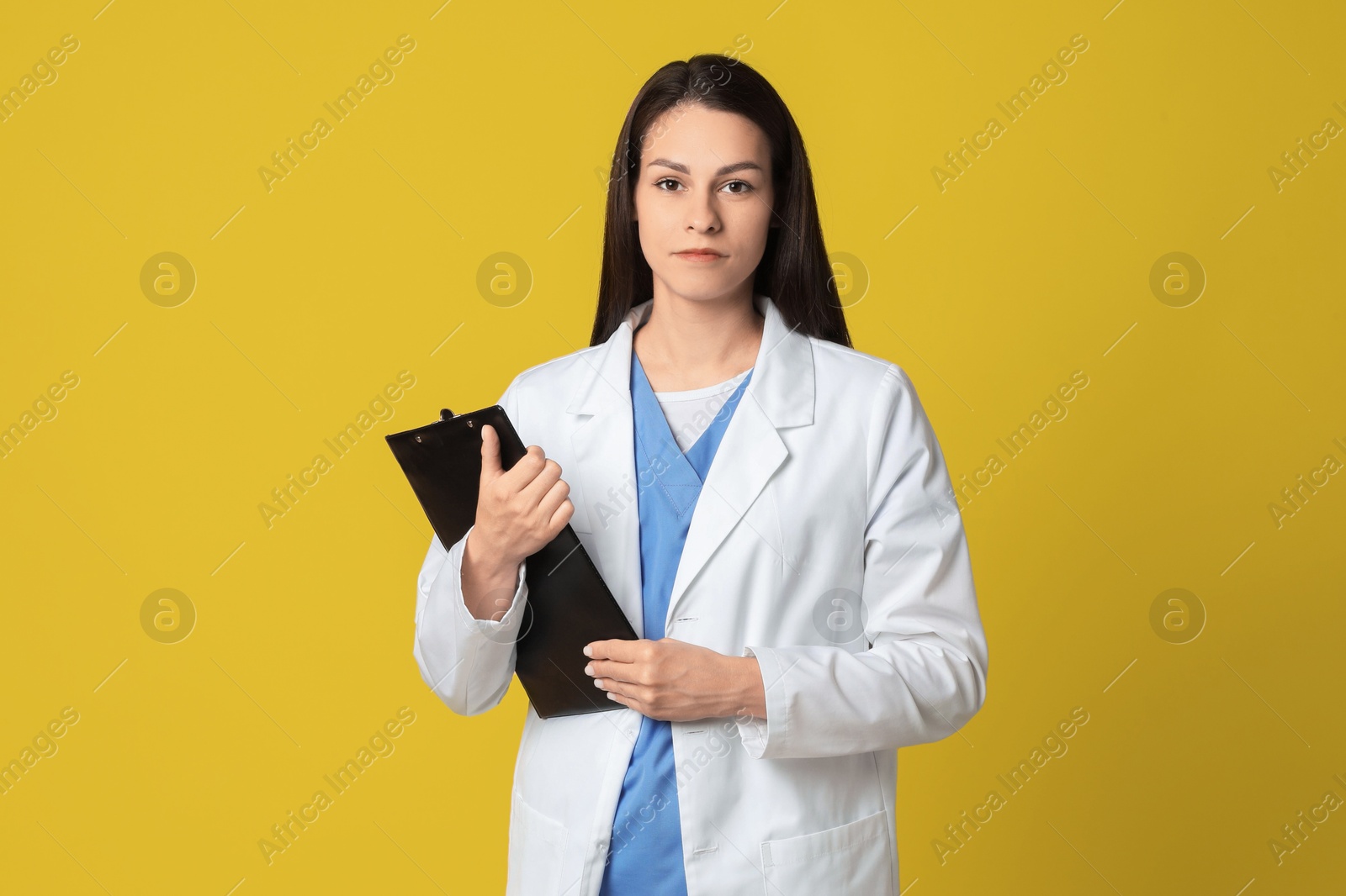 Photo of Portrait of beautiful nurse with clipboard on yellow background