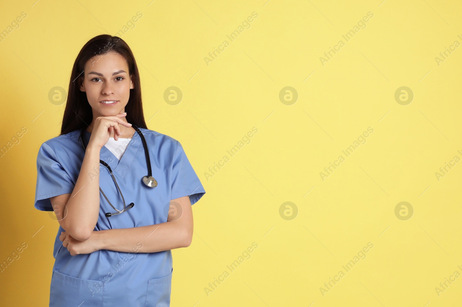 Photo of Portrait of smiling nurse with stethoscope on yellow background. Space for text