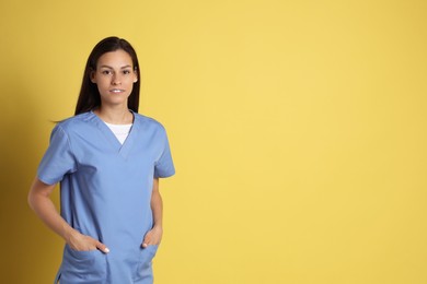 Portrait of beautiful nurse on yellow background. Space for text