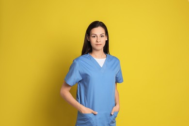 Portrait of beautiful nurse on yellow background