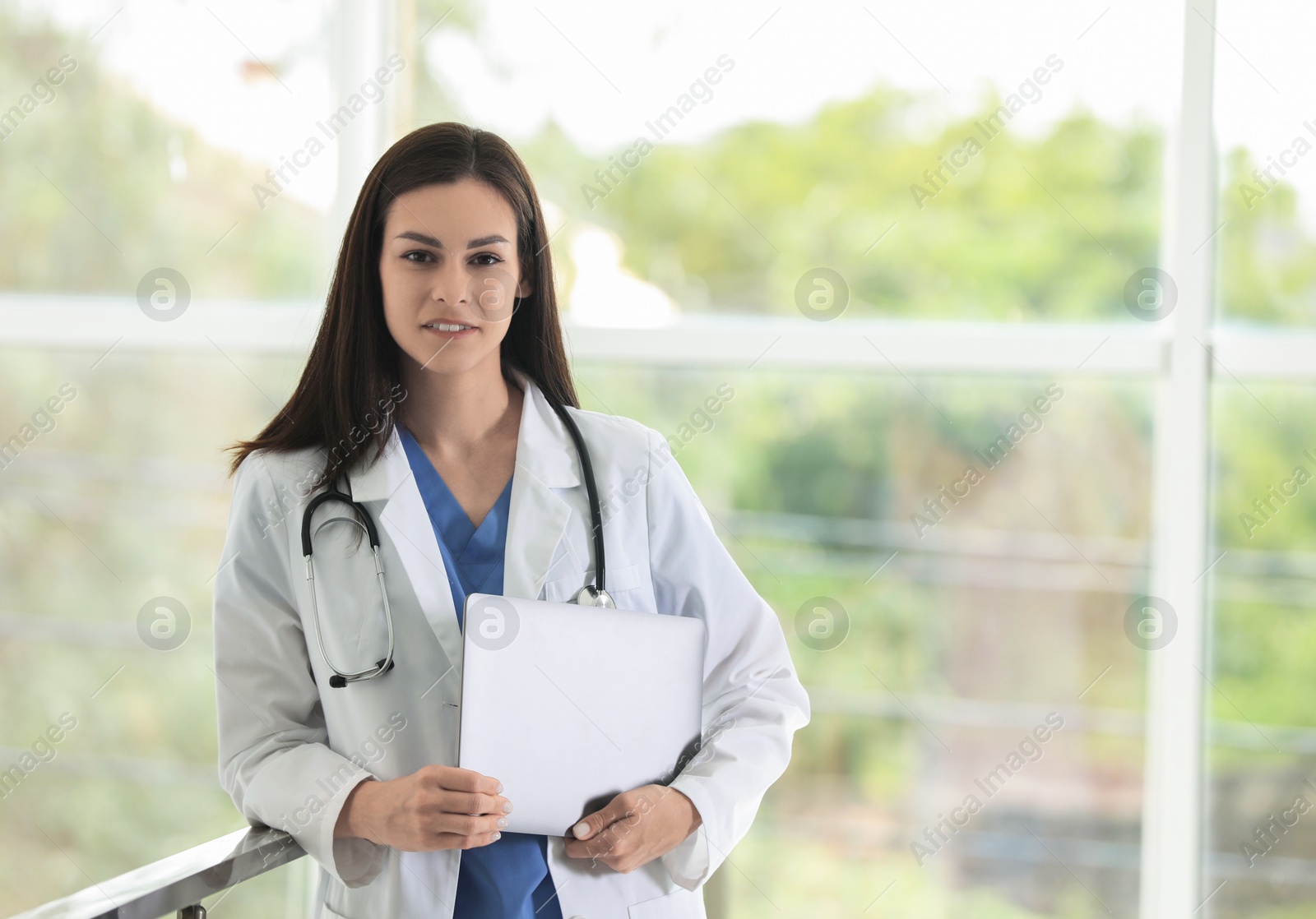 Photo of Smiling nurse with laptop in hospital. Space for text