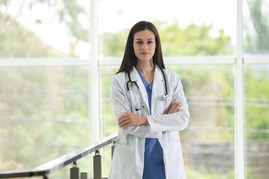 Beautiful nurse with stethoscope near railings in hospital