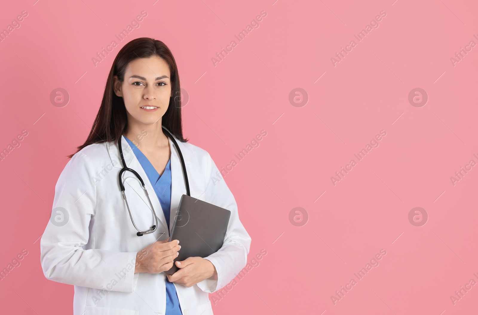 Photo of Smiling nurse with laptop on pink background. Space for text