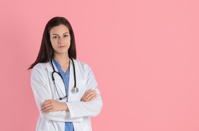 Photo of Beautiful nurse with crossed arms on pink background. Space for text