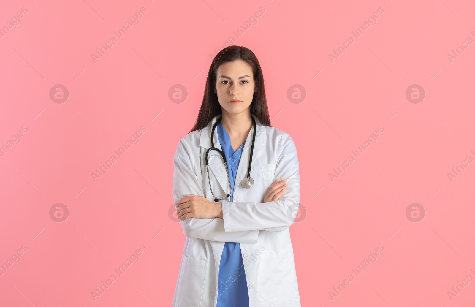 Photo of Beautiful nurse with crossed arms on pink background